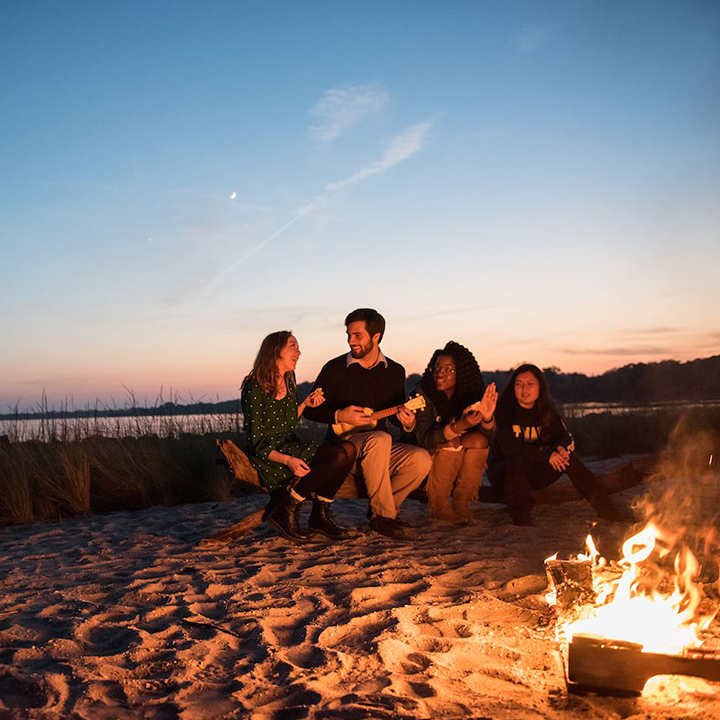 St Mary's College of Maryland students sitting on a beach around a fire