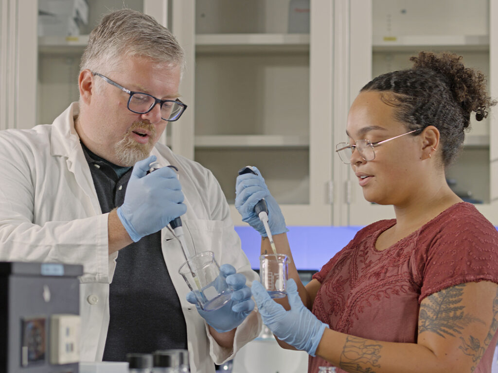 A student and professor working in a lab